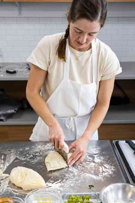 ATK Reviews member cutting pizza dough into portions.